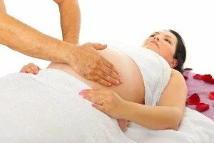 Therapist doing massage to pregnant woman tummy against white background