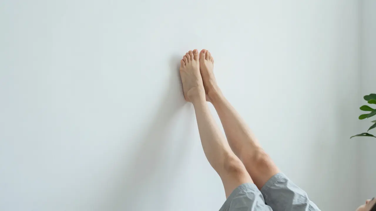 Person resting with legs up the wall, massaging foot acupressure point